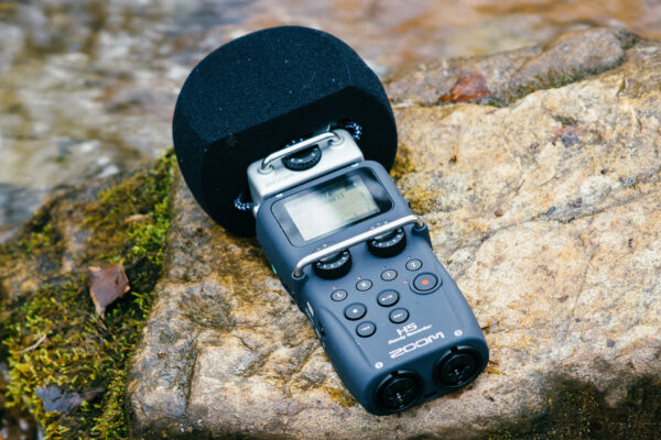 podcast recorder on a rock near a stream