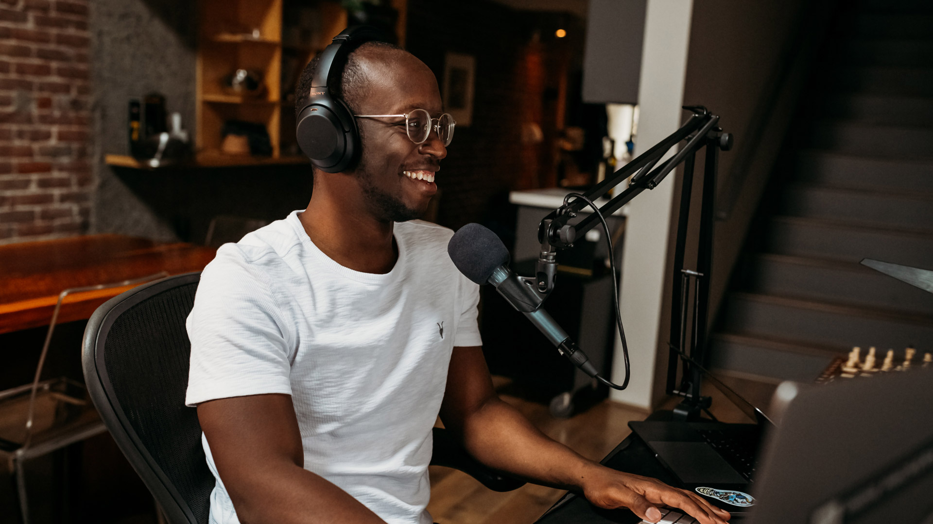 man hosting a podcast with headphones on in front of a microphone