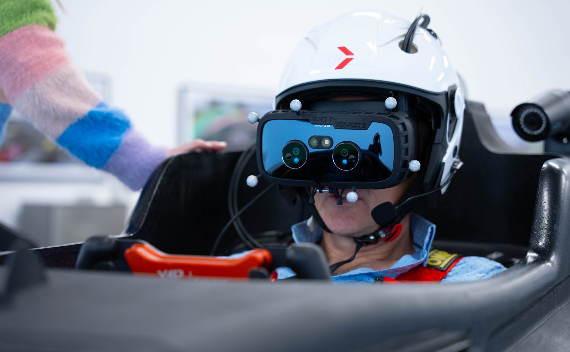 man sits in the cockpit of an F1 car simulator wearing a VR headset